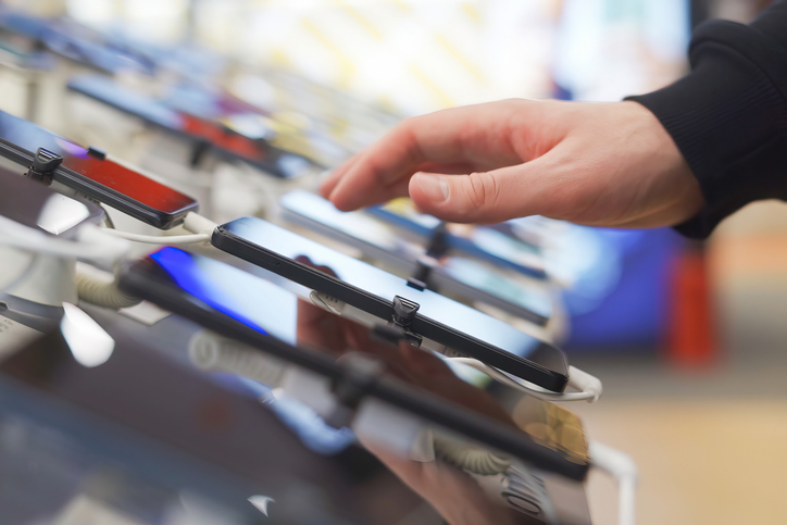 Hand of male buyer testing smartphone in electronics store